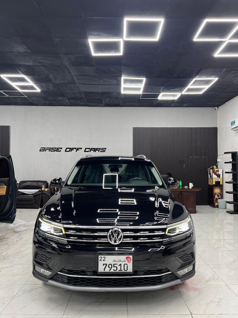A black SUV inside the Base off cars workshop, ceiling lights mirrored in the paintwork